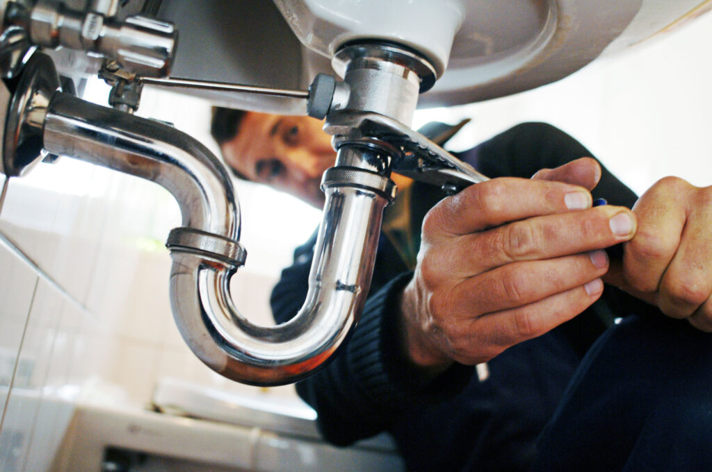 Close up of plumber repairing sink with tool in bathroom